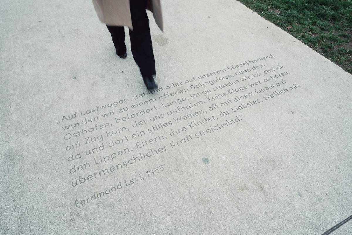 Ein Passant geht über eine Inschrift am Boden.