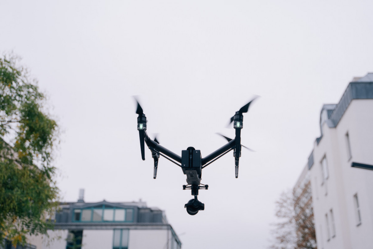 Eine Drohne fliegt zwischen Häuserzeilen hindurch.