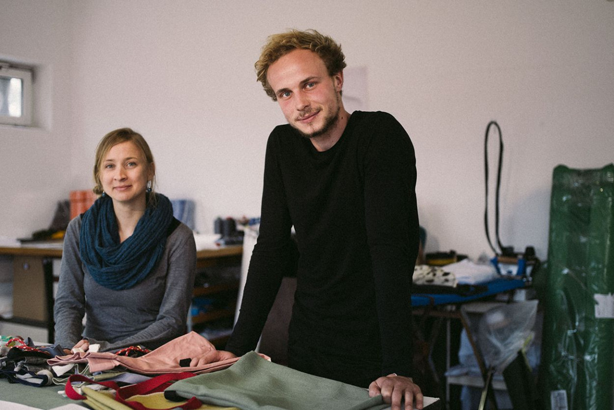 Ein junger Mann und eine junge Frau zeigen Taschen in einem Atelier