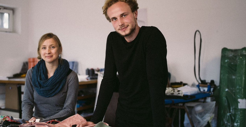 Ein junger Mann und eine junge Frau zeigen Taschen in einem Atelier