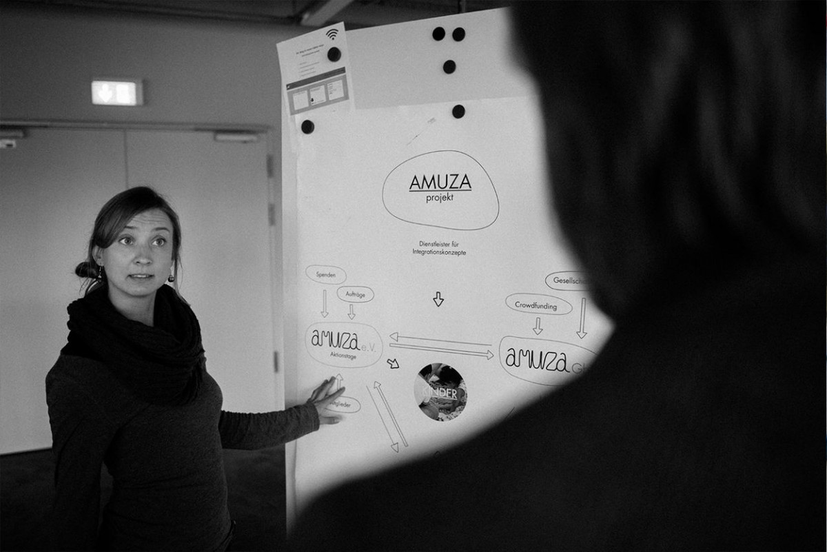 Eine junge Frau zeigt einem Zuseher eine Grafik an einem Flipchart