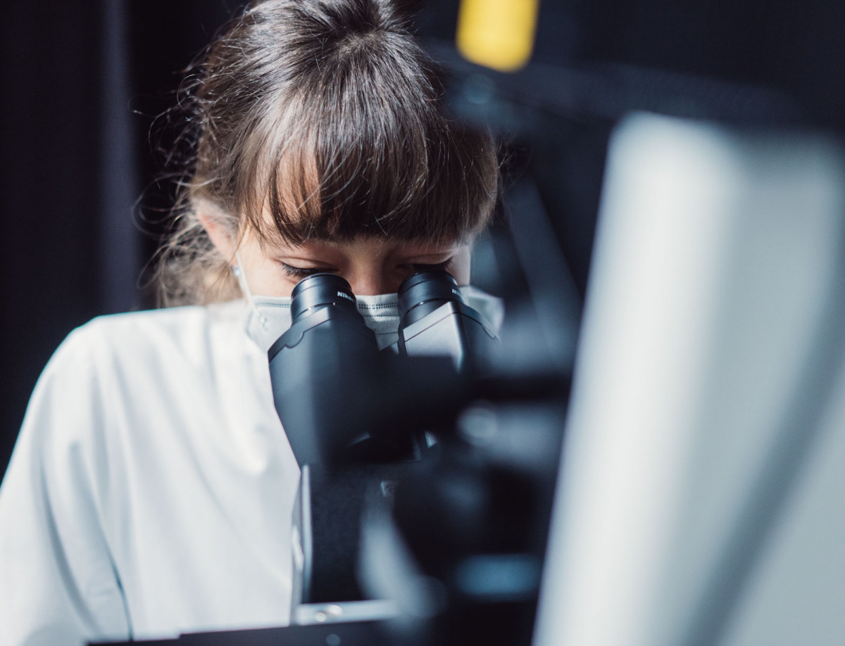 Katharina Becker von der Philipps-Universität Marburg schaut durch ein Mikroskop.