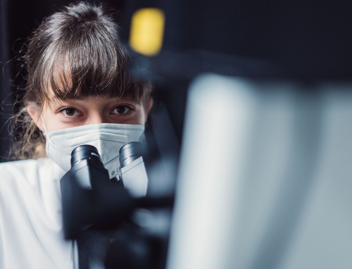 Katharina Becker von der Philipps-Universität Marburg schaut durch ein Mikroskop.