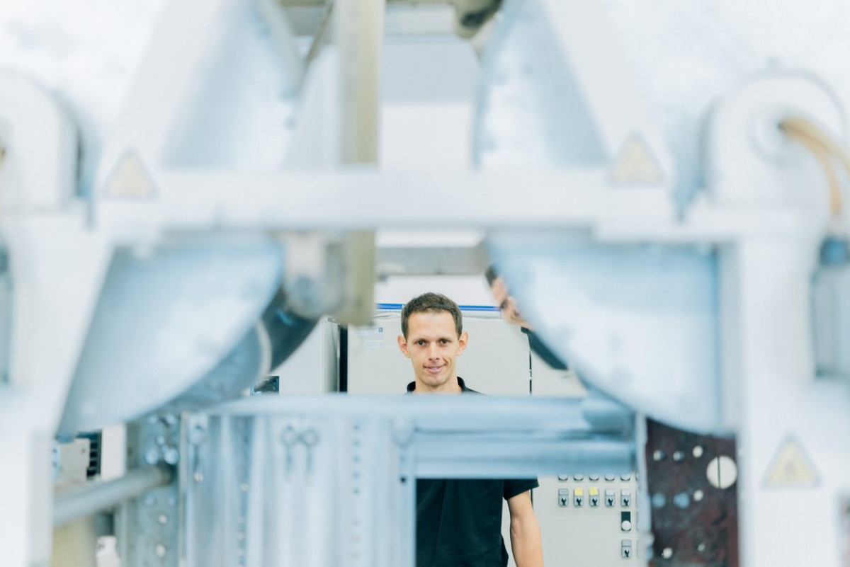 Robert Götzinger hinter einer Maschine am LOEWE-Schwerpunkt „BAMP! – Bauen mit Papier“ der TU Darmstadt.