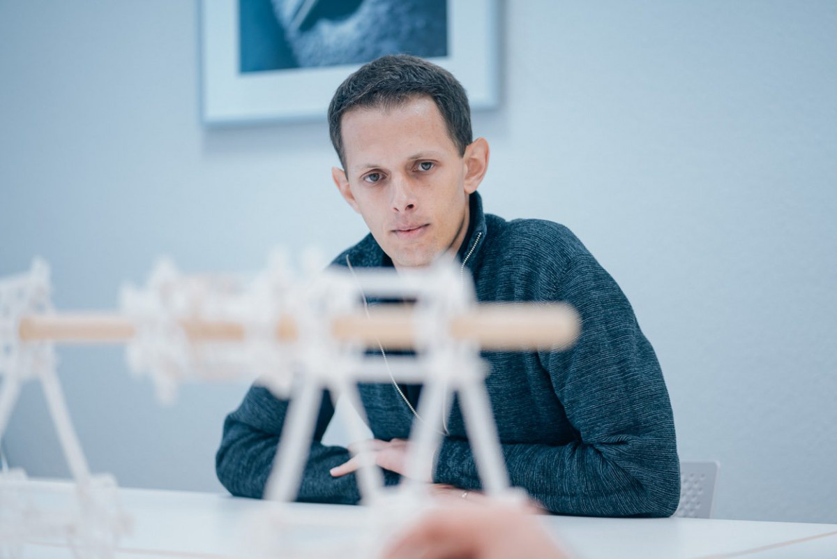 Robert Götzinger sitzt hinter einem Modell aus Papier.