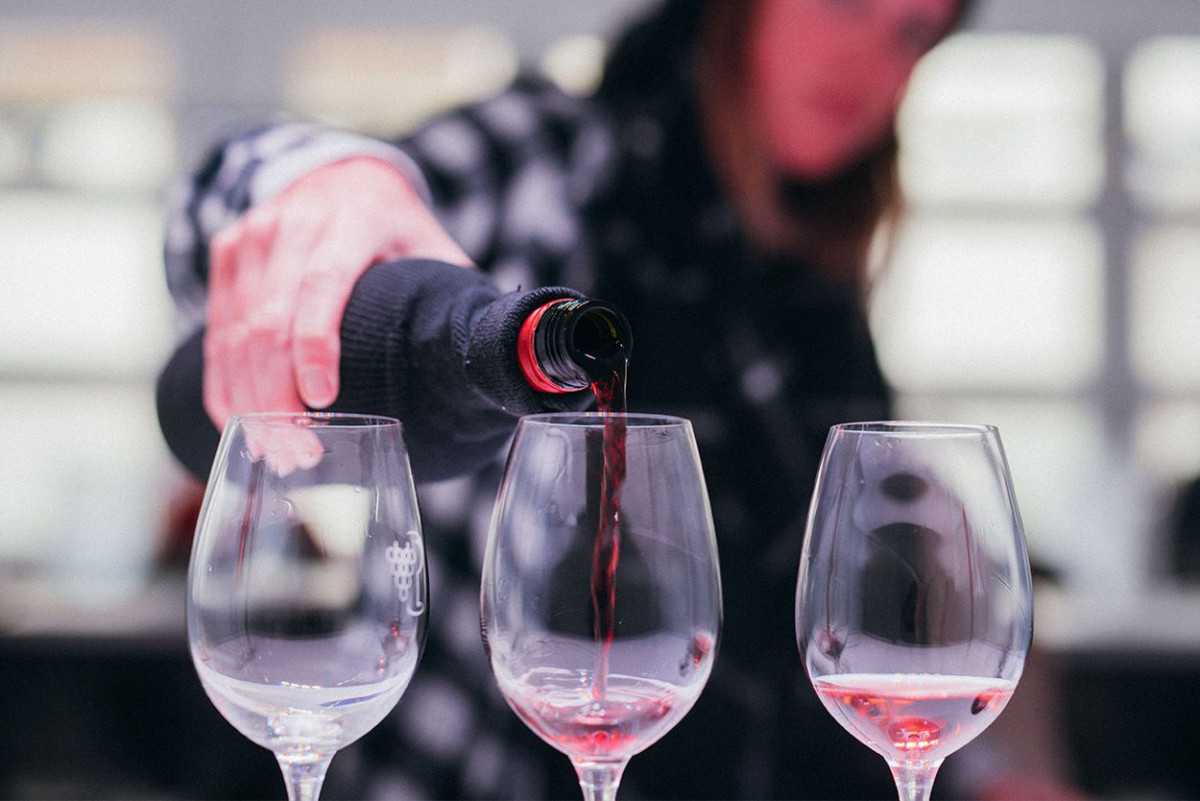 Eine junge Frau gießt Rotwein in Weingläser