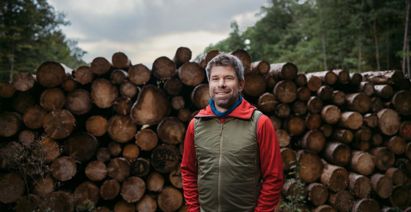 Prof. Dr. Thomas Nauss vor einem Stapel Baumstämme
