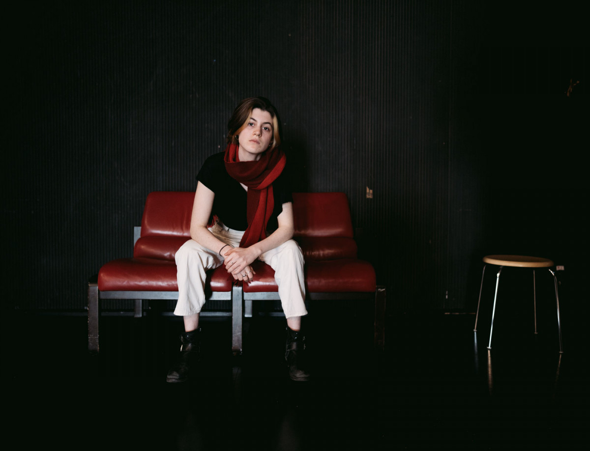 Schauspielstudentin Fenna sitzt in der Mitte von zwei roten Ledersesseln.