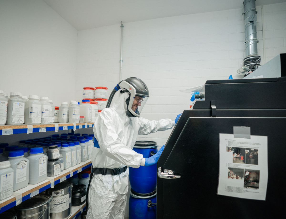 Moritz Kahlert vom Fachgebiet Metallische Werkstoffe arbeitet in Schutzkleidung an einem Metalldrucker.