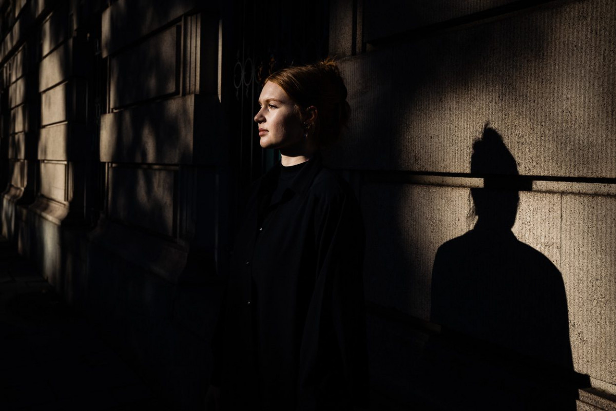 Mirjam Motzke mit Schatten im Dunkeln vor einer Häuserwand