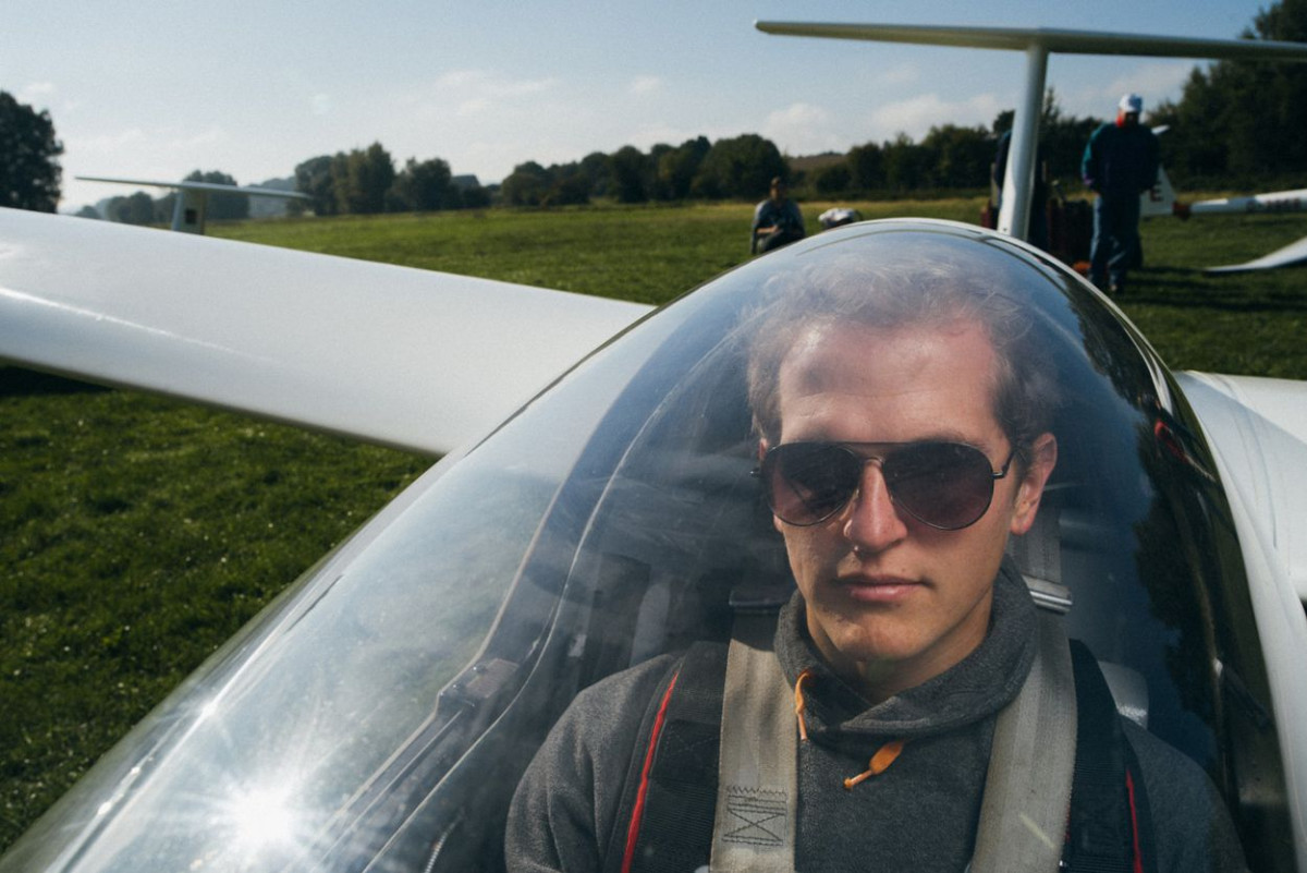 Ein junger Mann mit Sonnenbrille sitzt in einem Segelflugzeug