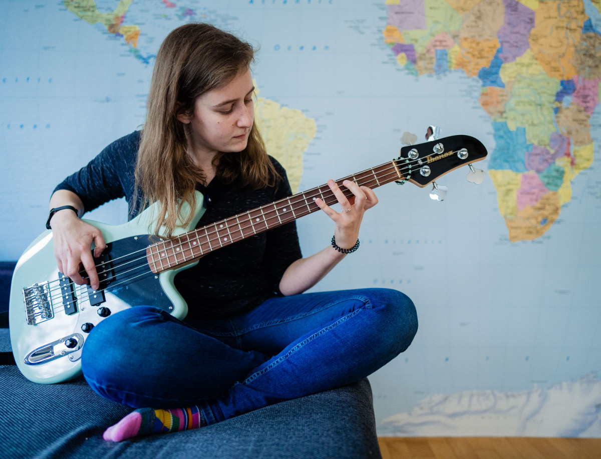 Hannah spielt vor ihrer Weltkarte Gitarre.