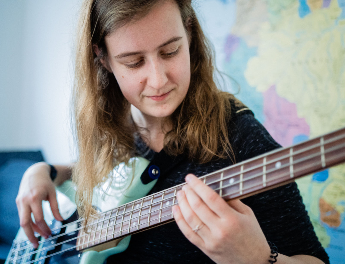 Hannah spielt vor ihrer Weltkarte Gitarre.