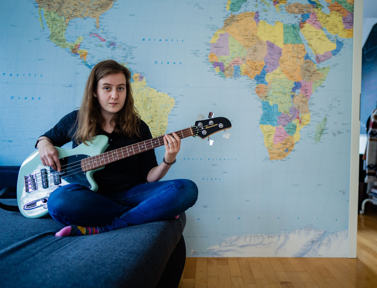 Hannah spielt vor ihrer Weltkarte Gitarre.