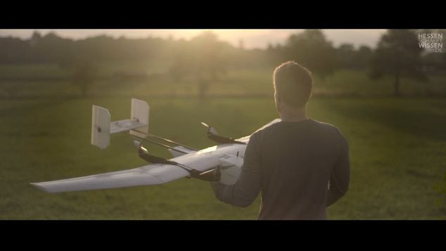 Ein junger Mann hält ein Segelflugzeug in der Hand