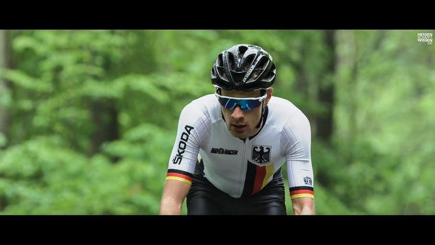 Ein Student der Technischen Universität Darmstadt fährt auf einem Fahrrad durch den Wald