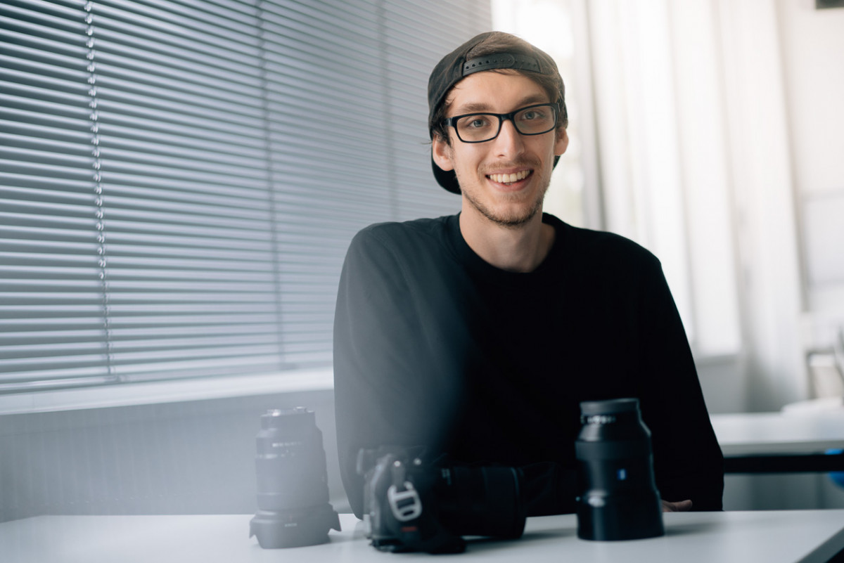 Student Jonas Keiner vor einer Auswahl von Kameraobjektiven.