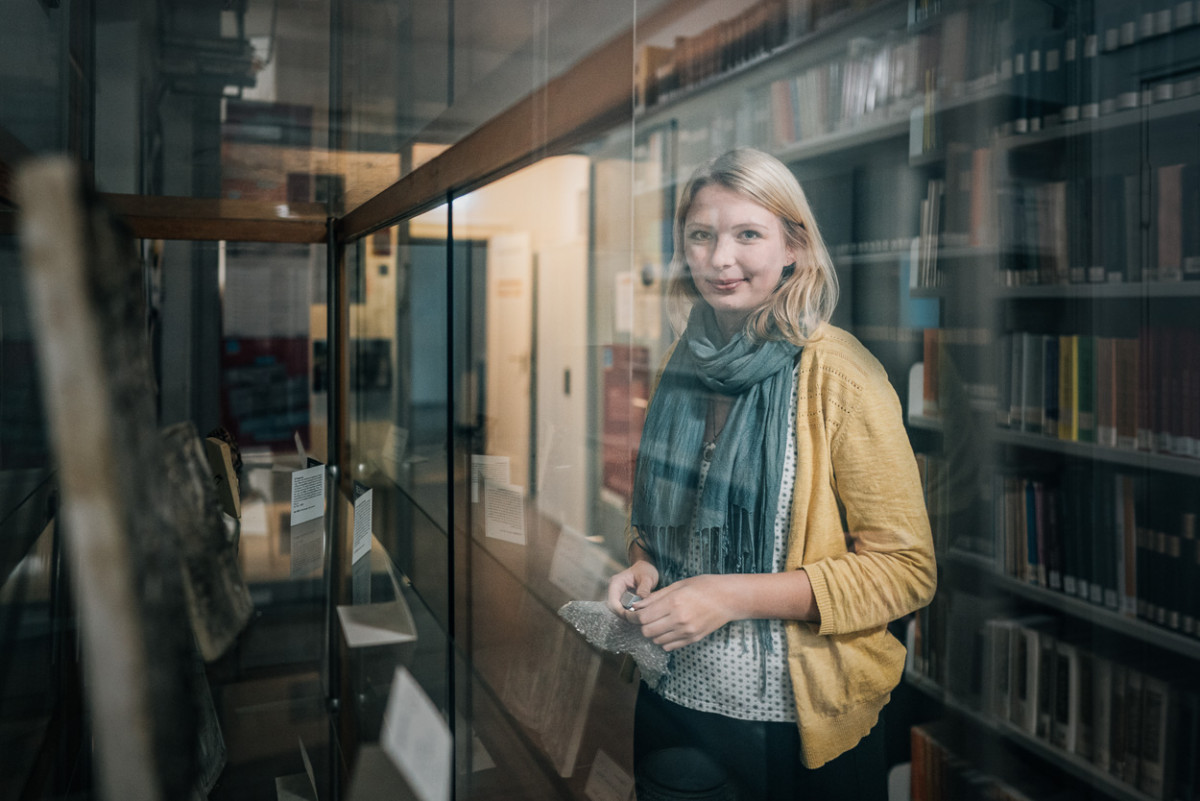 Studentin Alieda Halbersmah steht vor einer Vitrine mit historischen Artefakten.