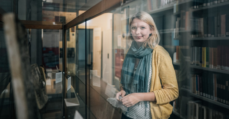 Studentin Alieda Halbersmah steht vor einer Vitrine mit historischen Artefakten.