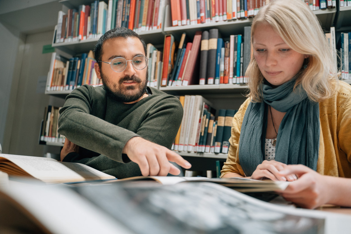 Die Studierenden Hüseyin Çinarlik und Alieda Halbersmah betrachten ein historisches Dokument im Archiv.