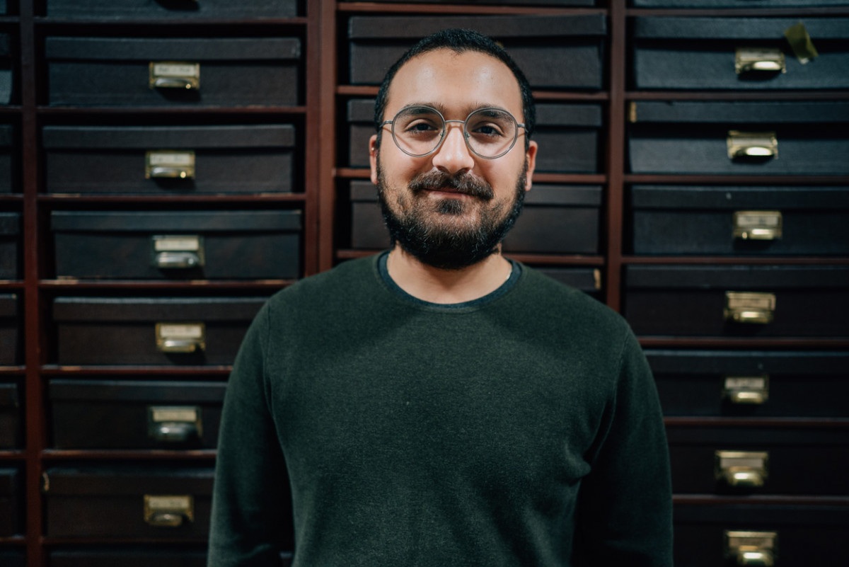 Archeologiestudent Hüseyin Çinarlik vor einem Schrank in der Bibliothek.