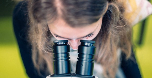 Eine Studentin schaut in ein Mikroskop