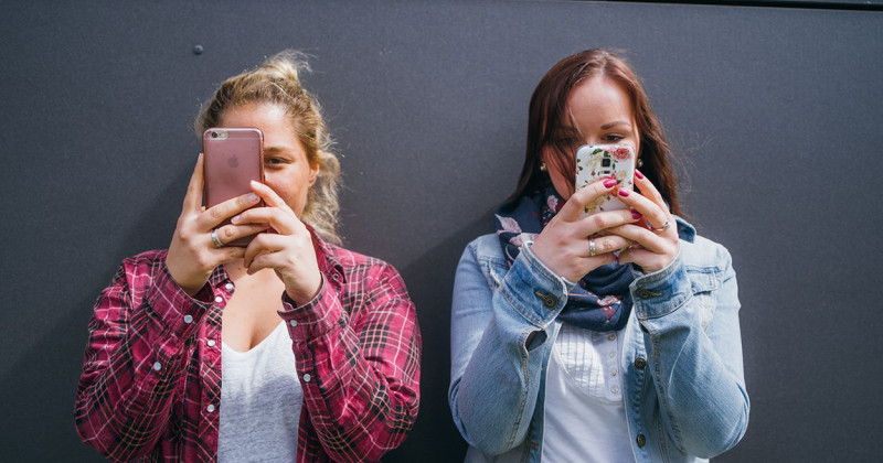 Zwei junge Studentinnen schauen auf ihre Smartphones